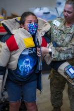 Senior Master Sergeant Lindsay Rickert helps student get into 80 lb bomb suit
